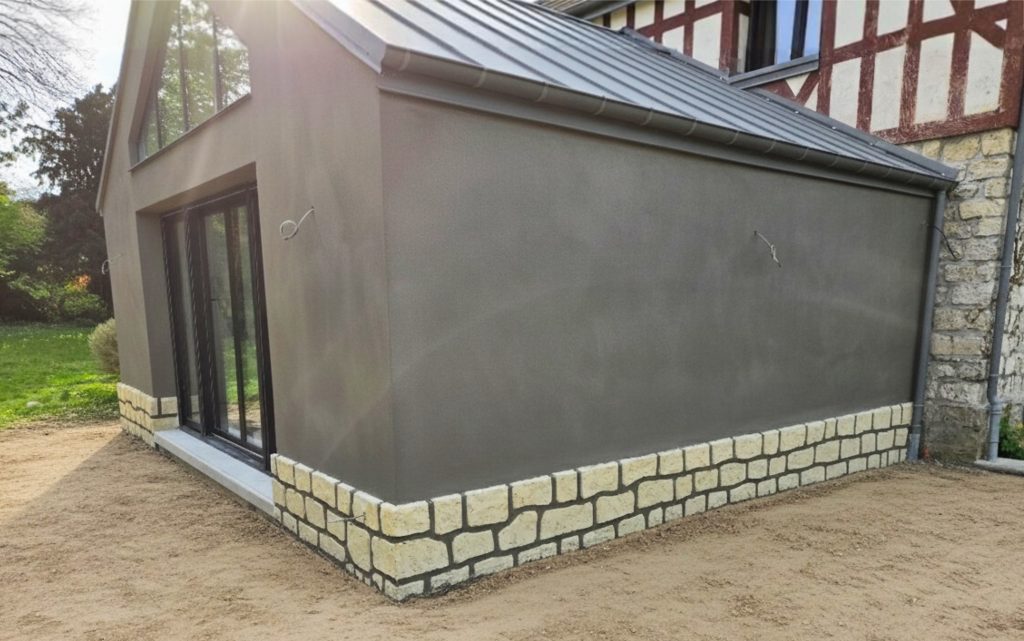 Façade d'une extension de maison moderne avec enduit gris anthracite lissé et création d'un soubassement imitation pierre dans l'Oise.